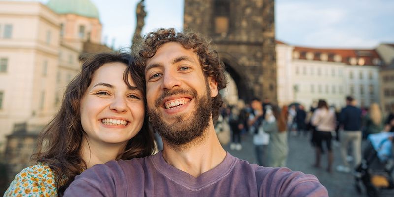 Ein Paar macht ein Selfie auf der Karlsbrücke in Prag, Tschechien, und fängt damit die Romantik einer der bezauberndsten Städtereisen Europas ein.