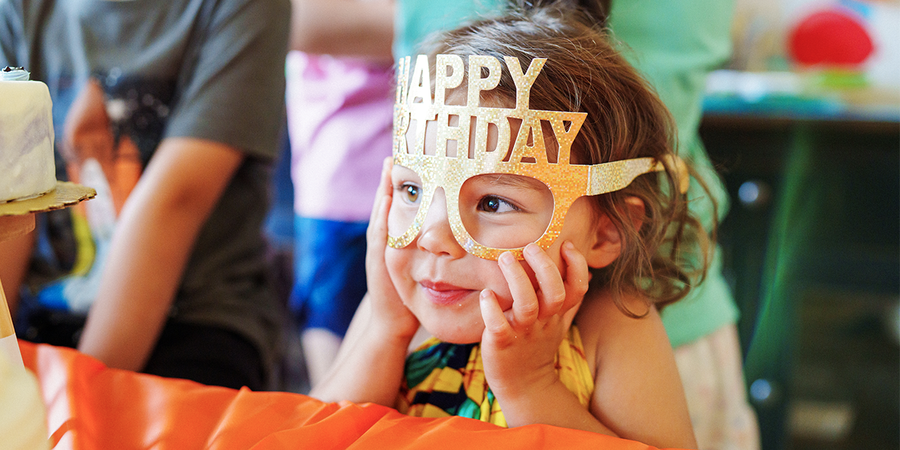 Ein kleines Mädchen mit einer Happy Birthday-Partybrille, passend zu einem personalisierten Geburtstagsgeschenk oder einem individuellen Geburtstagsgeschenk von posterXXL.
