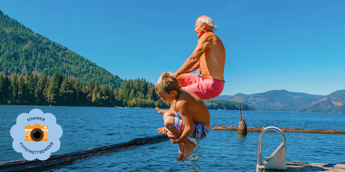 Ein älterer Mann und ein junger Junge springen ins Meer und halten einen fröhlichen Sommermoment für den posterXXL Sommer-Fotowettbewerb fest.