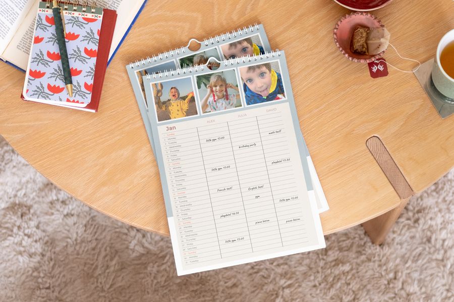 Personalisierter posterXXL Familienplaner, der prominent auf einem Holztisch präsentiert wird.