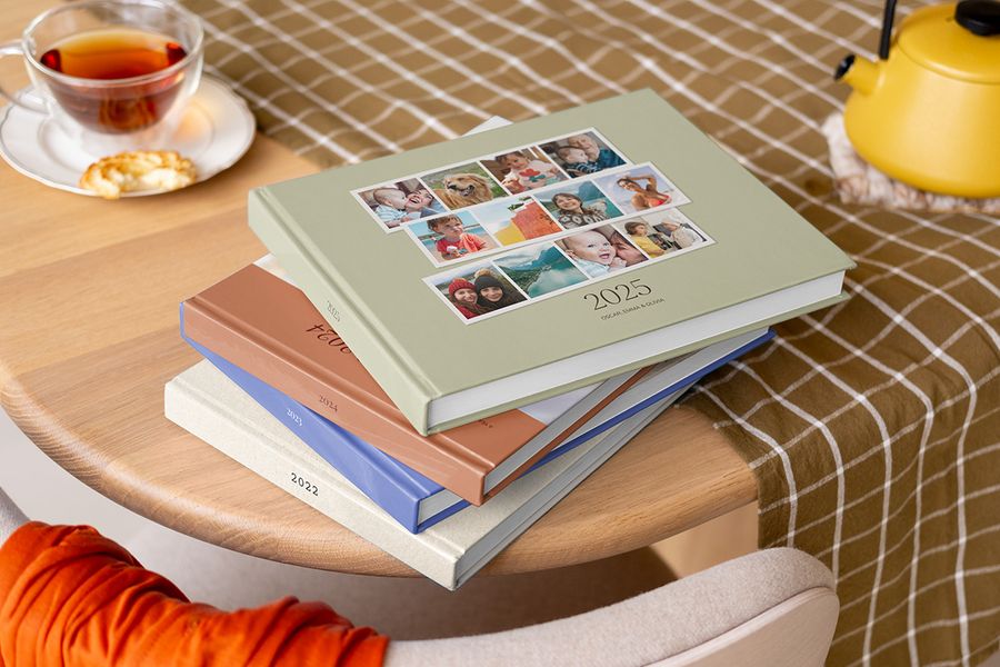 Mehrere Foto-Jahrbücher mit Hardcover und verschiedenen Jahreszahlen auf einem Couchtisch gestapelt.