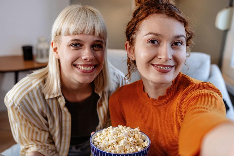 Zwei beste Freundinnen teilen sich Popcorn für einen gemütlichen Filmabend am Galentine's Day – der Beweis, dass der Valentinstag auch für Freunde zum gemeinsamen Genießen mit posterXXL da ist.
