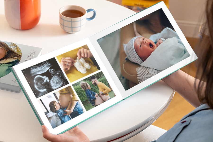 Ein geöffnetes fotobuch mein erstes jahr, das auf der linken Seite einen Babybauch, ein Ultraschallbild und Babyschuhe zeigt, und ein Foto eines neugeborenen Babys auf der rechten Seite.