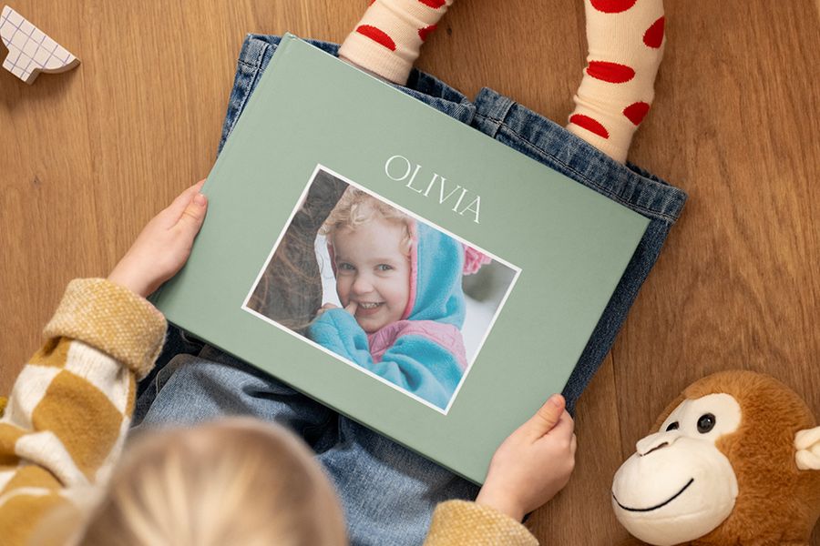 Personalisiertes Baby-Fotobuch mit einem glücklichen Mädchen, ideal um fotobuch sprüche geburtstag und schöne sprüche für fotoalbum zu finden.