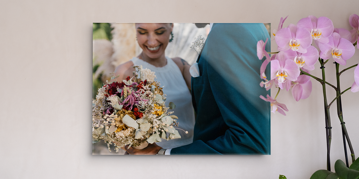 Eine personalisierte leinwand hochzeit von posterXXL mit einer lächelnden Braut und ihrem Brautstrauß, dekoriert neben einer Orchidee.
