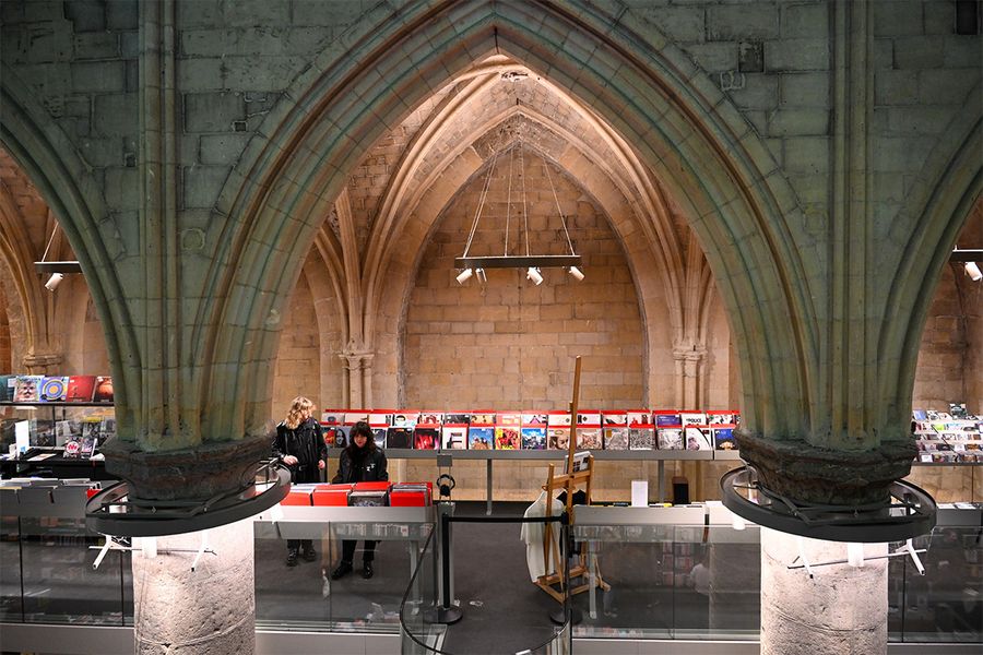 Boekhandel Dominicanen in Maastricht, eine Buchhandlung in einer 700 Jahre alten gotischen Kirche mit hohen Regalen und Steingewölben, perfekt für Literaturreisen mit posterXXL.