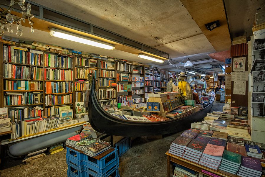 Die Buchhandlung Libreria Acqua Alta in Venedig, Italien, mit Büchern in einer Gondel und Badewannen zum Schutz vor Hochwasser, ein kurioses Highlight für Literaturreisen mit posterXXL.