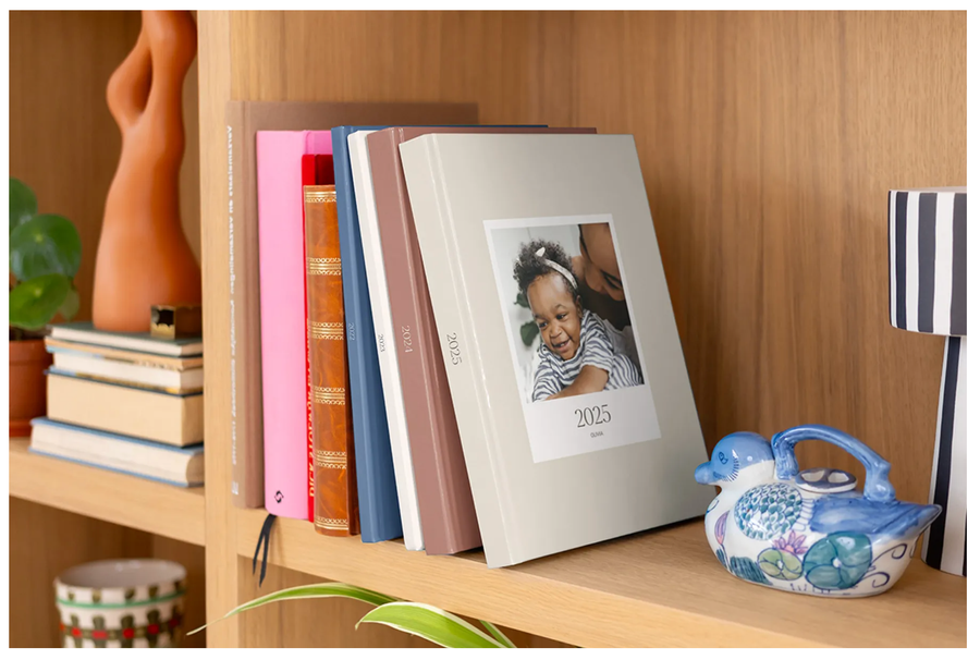 Ein Regal mit geschlossenen Hardcover-Premium-Layflat-Jahrbüchern von posterXXL, ideal als hochwertige fotobücher für das ganze Jahr.