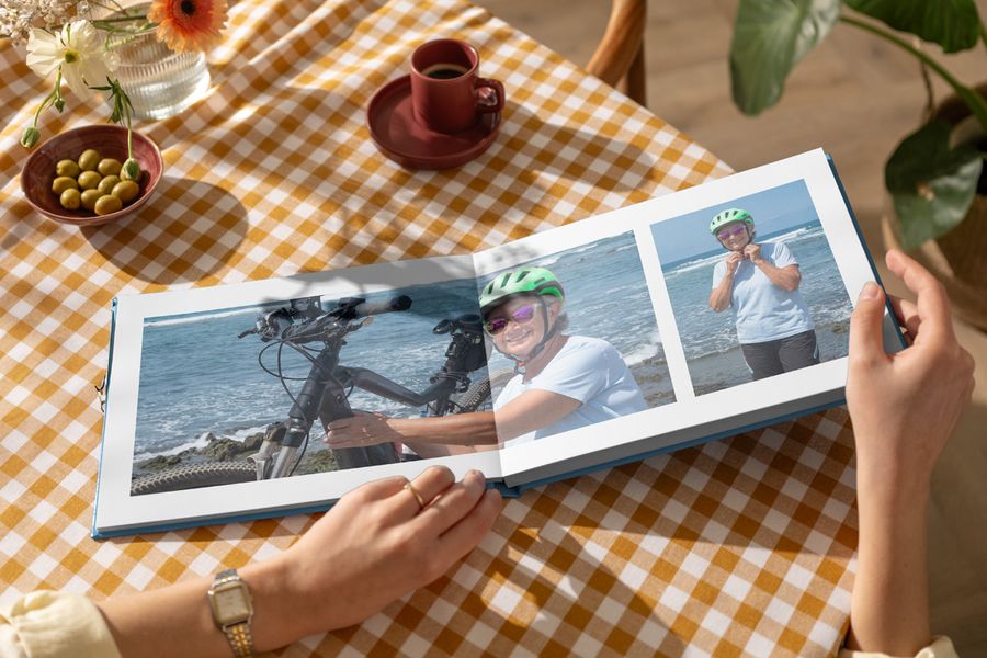 Ein geöffnetes personalisiertes posterXXL Fotobuch mit einer Doppelseite, die eine ältere Frau in Fahrradkleidung am Strand zeigt – als Inspiration für ein Fotobuch zum Muttertag und ein persönliches Muttertagsgeschenk.