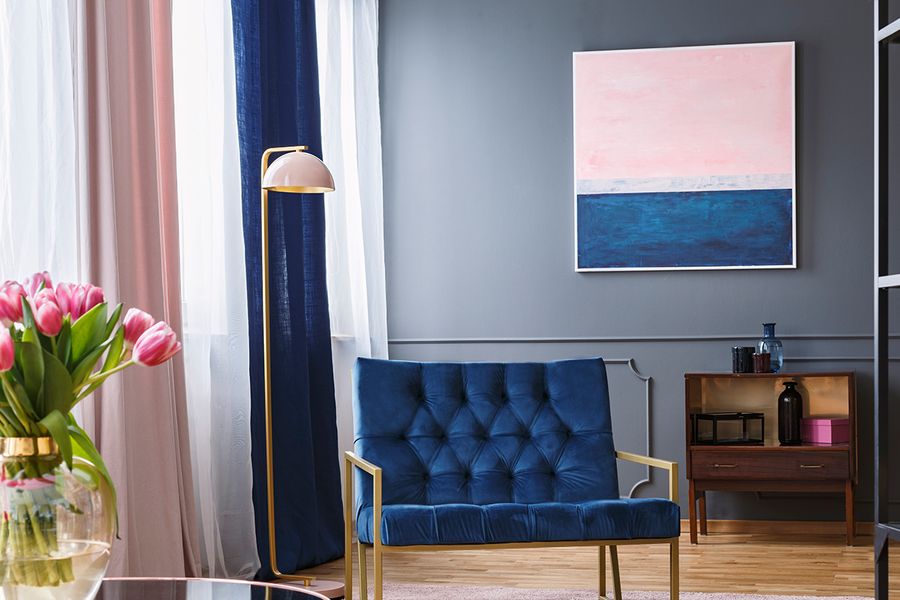 Ein Wohnzimmer in Marineblau und Rosa mit einem blauen Samtsofa, bunten Vorhängen und rosa Tulpen, ein Beispiel für mieterfreundliche Vorhänge und Deko bei posterXXL.