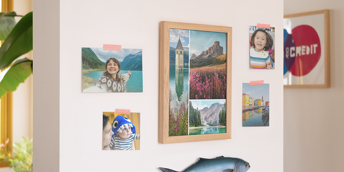 posterxxl Fotoabzüge an einer Wand im Zuhause, mit einem großen Rahmen voller Landschaftsbilder und vier einzelnen Familienfotos an der Wand – als Inspiration für Fotoabzüge und Fotos online bestellen.