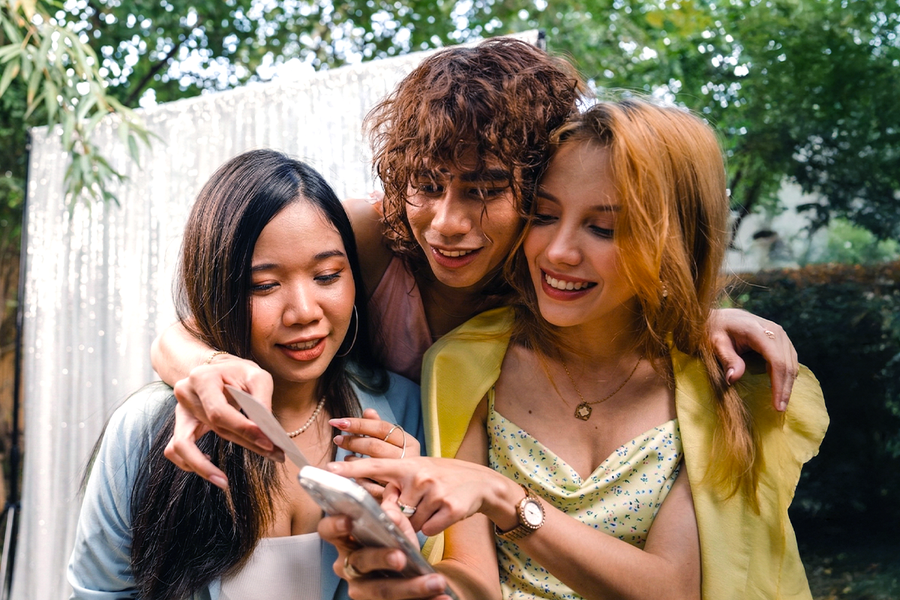 Drei Freunde in festlicher Hochzeitskleidung machen bei einer Foto-Schnitzeljagd auf einer Hochzeit mit – als Inspiration für posterXXL Hochzeitsspiele und lustige Hochzeitsspiele für Gäste.