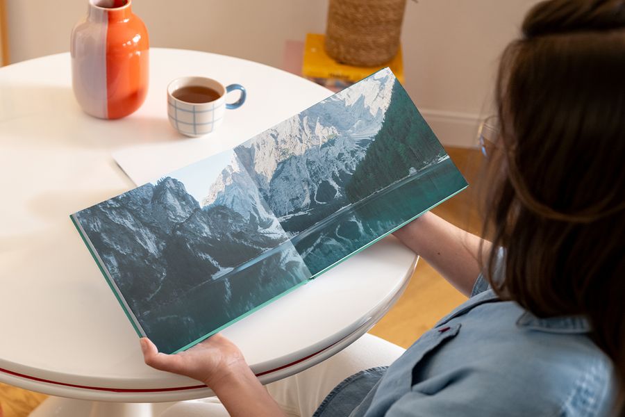 Ein geöffnetes posterXXL Coffee Table Fotobuch mit einer Doppelseite, die eine Berglandschaft mit See zeigt – als Inspiration für ein Photography Coffee Table Book und ein personalisiertes Coffee Table Book.