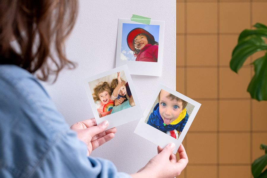 Eine Frau hält personalisierte posterXXL Fotoabzüge in der Hand – als Inspiration für Kinderparty Geschenke und kleine Mitgebsel für Gäste.
