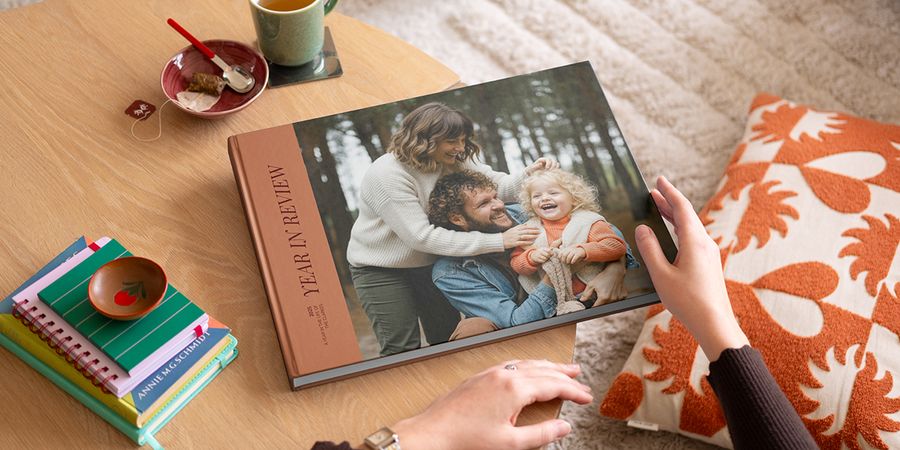 Ein posterXXL Coffee Table Fotobuch im Year-in-Review-Stil mit einem attraktiven Familienfoto auf dem Cover, das auf einem Couchtisch liegt – als Inspiration für ein personalisiertes Coffee Table Book.
