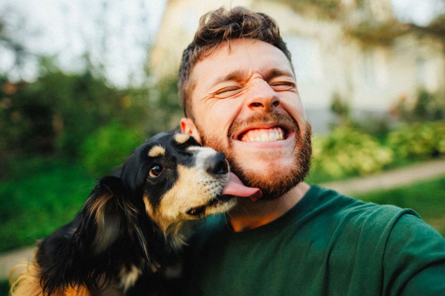 Ein Mann lächelt mit seinem Hund – als Inspiration für eine Vatertagskarte vom Hund und lustige Texte für Hundepapas.