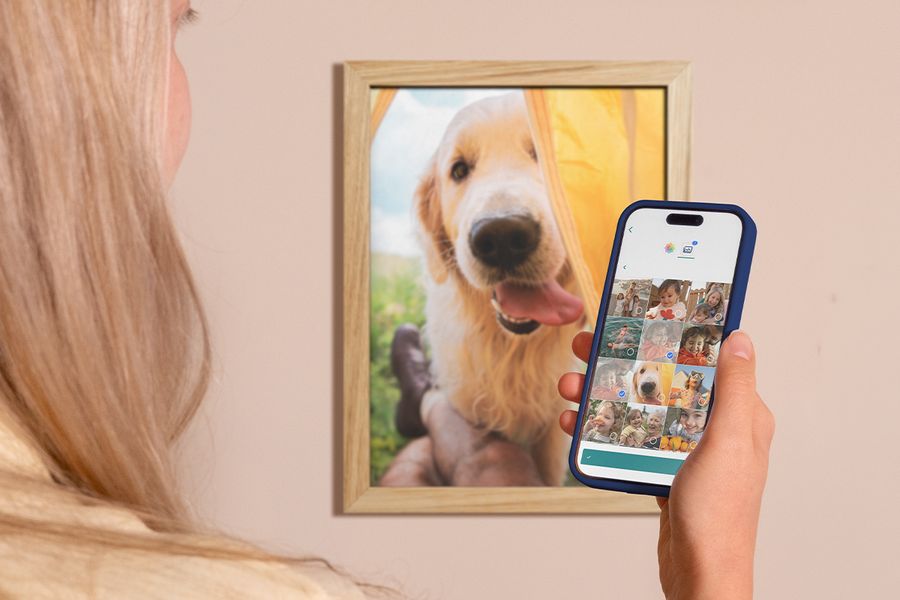 Eine Frau schaut auf ihrem Smartphone ihre Kamerarolle durch, während hinter ihr ein gerahmtes Labrador-Bild an der Wand hängt – eine Inspiration, um digitale Fotos zu organisieren und die schönsten Momente auszuwählen.