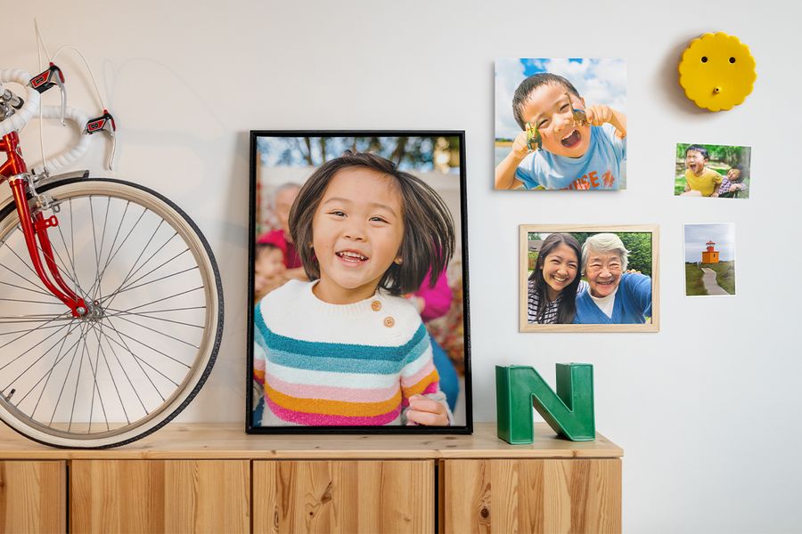 Verschiedene Familienfotos sind in unterschiedlichen Anordnungen an einer Wand neben Wohnaccessoires und Wanddeko präsentiert – als Inspiration für Fotowand Ideen und frische Deko in der Wohnung.