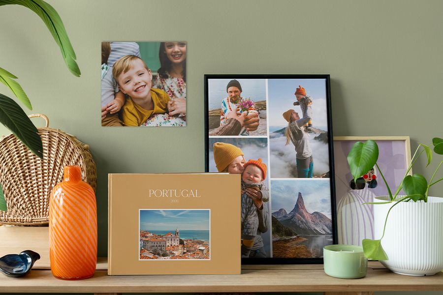 Ein personalisiertes Reise-Fotobuch steht neben einer gerahmten Fotocollage und einem Familienfoto an der Wand – als Inspiration, wie Fotos dein Zuhause persönlicher und wohnlicher machen können.