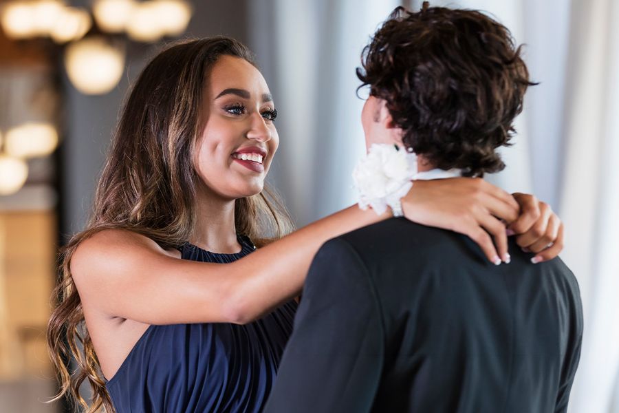 Junges Paar in festlicher Kleidung schaut sich beim Abiball an und posiert natürlich für ein romantisches Pärchenbild