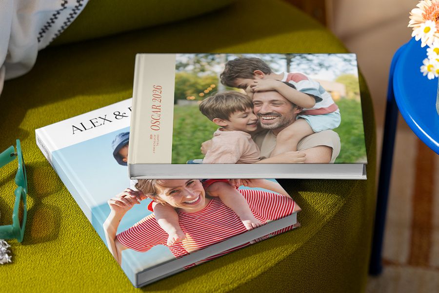 Zwei verschiedene posterXXL Urlaubsfotobücher mit Familienfotos auf dem Cover, die Eltern, Kinder, einen Namen und das Jahr zeigen, veranschaulichen bewährte Tipps für ein personalisiertes Reise-Fotobuch.
