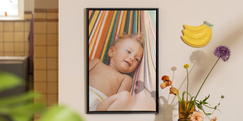 Personalisierte posterXXL Wanddeko mit einem Babyfoto neben Blumen und Fruchtdeko – als Inspiration für sommerliche Deko Ideen zu Hause.