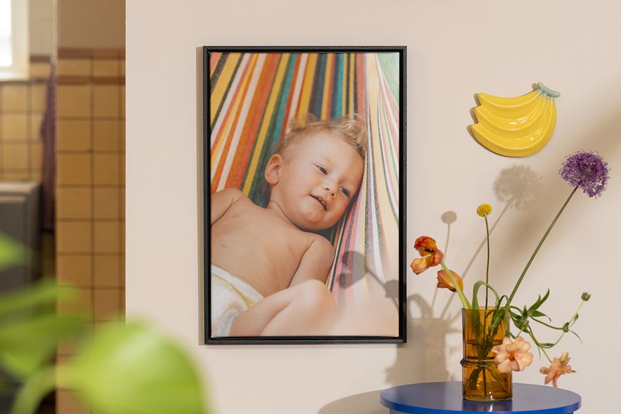 Personalisierte posterXXL Wanddeko mit einem Babyfoto neben Blumen und Fruchtdeko – als Inspiration für sommerliche Deko Ideen zu Hause.