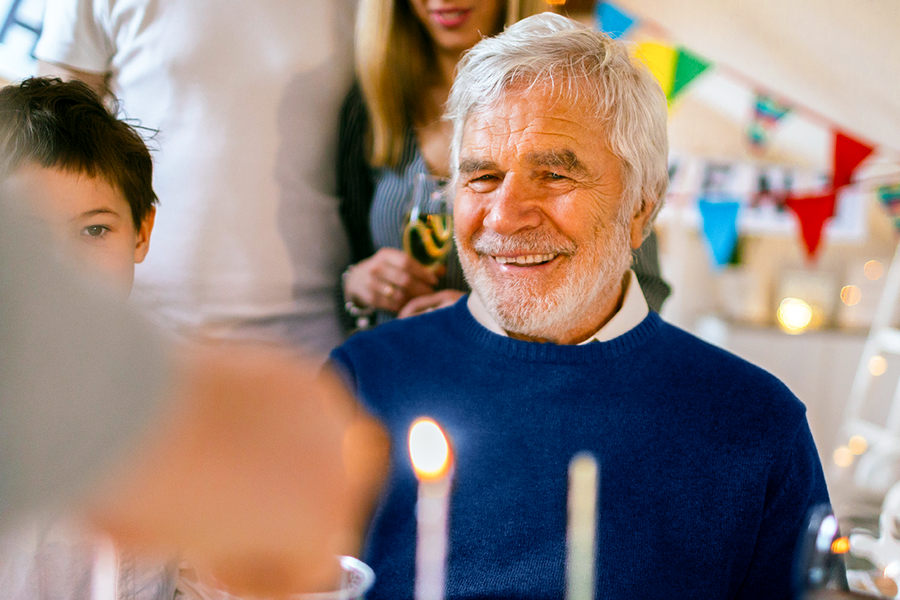 Ein lächelnder Großvater bei seiner Geburtstagsfeier; ein schönes Motiv für ein persönliches Geschenk zum 80. Geburtstag oder Fotogeschenke zum Geburtstag von posterXXL.