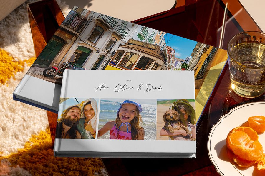 Zwei verschiedene posterXXL Reise-Fotobücher sind zusammen zu sehen, darunter ein Urlaubsfotobuch im Querformat mit Familienreisefotos auf dem Cover und ein weiteres mit einer Straßenbahn im Urlaubsmotiv – als Inspiration für verschiedene Reise-Fotobuch-Ideen.