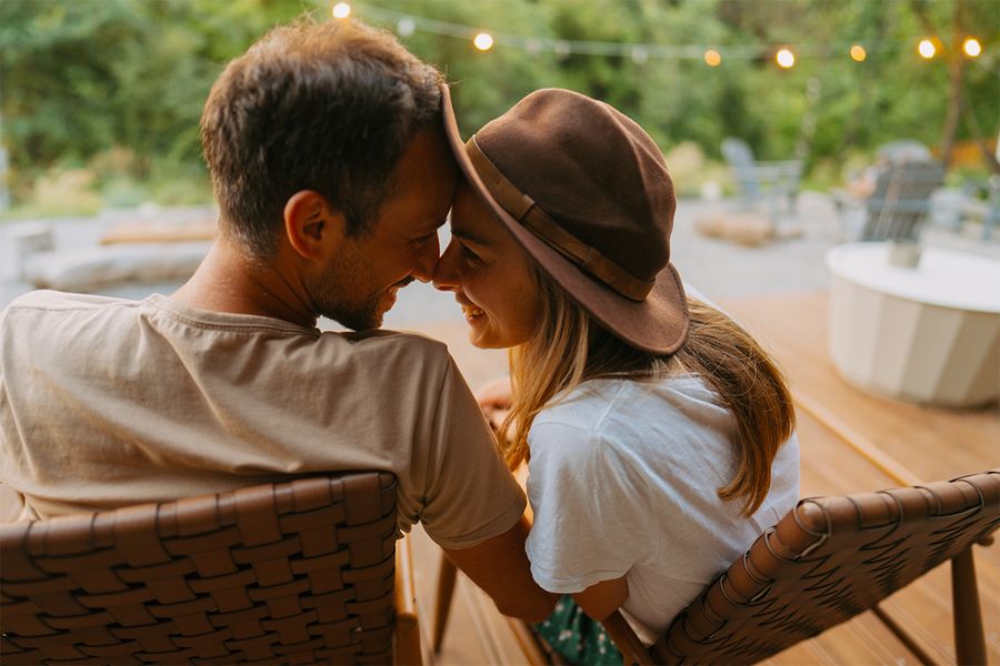 Ein Mann und eine Frau kuscheln in einem mit Lichterketten geschmückten Garten, ein romantischer Moment aus posterXXLs Staycation-Ideen für Paare.