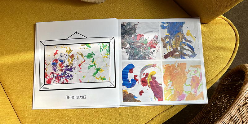 Ein aufgeschlagenes Kinderfotobuch liegt auf einem gelben Sessel, mit den ersten Farbklecksen eines kleinen Kindes auf der linken Seite und vier verschiedenen Gemälden auf der rechten Seite, das posterXXLs Ideen für ein Kinderfotoalbum veranschaulicht.
