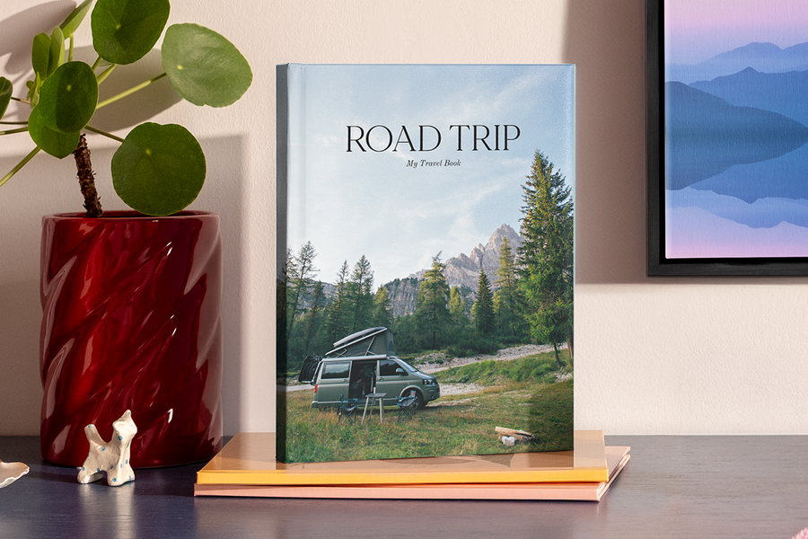 Ein großes Hochformat-Fotobuch zeigt ein Bild eines Wohnmobils in einer bergigen, nationalparkähnlichen Landschaft, und veranschaulicht posterXXLs Fotobuch Titel Ideen für einen Roadtrip.