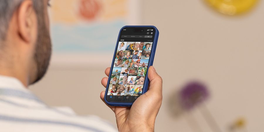Ein Mann hält sein Smartphone hoch und scrollt durch seine Kamerarolle, und veranschaulicht posterXXLs Ratgeber zum Umgang mit Fotoüberlastung und zum Aufräumen der Fotos.