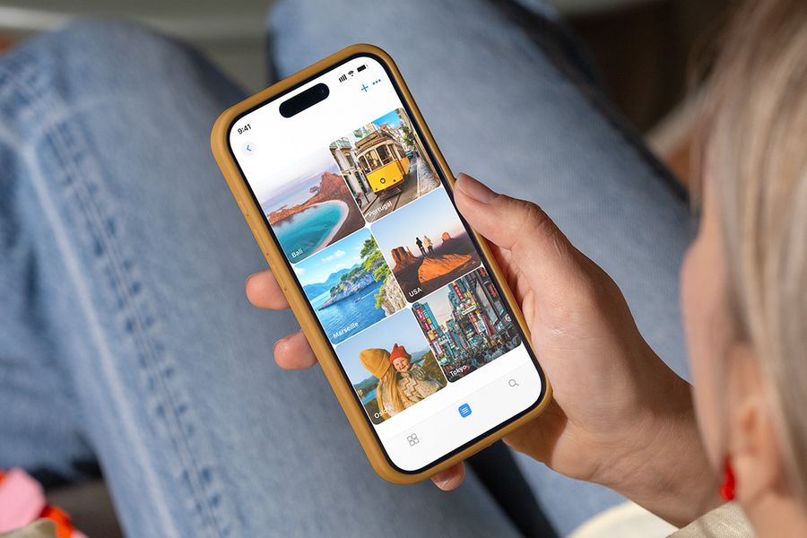 Eine Person betrachtet Fotoordner auf ihrem Handy, die nach Urlaubszielen wie 'Bali' und 'Tokio' benannt sind, und veranschaulicht posterXXLs Tipps zum Organisieren von Fotos, die zum Drucken bereit sind.