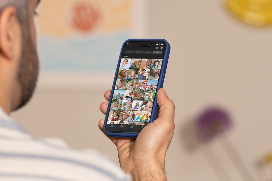 Ein Mann hält sein Smartphone hoch und scrollt durch seine Kamerarolle, und veranschaulicht posterXXLs Ratgeber zu den besten Tools zum Organisieren von Fotos.