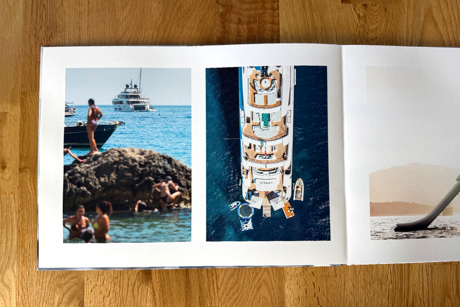 Eine aufgeschlagene Doppelseite aus Charl van Rooys Fotobuch zeigt Urlaubsstrandszenen, mit Menschen, die sich am Meer entspannen, und einer Jacht, und veranschaulicht den visuellen Fluss seines Fotografie-Portfolios.