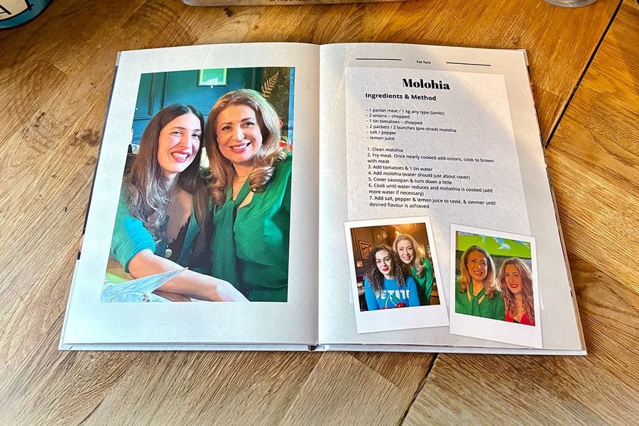 Eine Doppelseite aus Sarahs persönlichem Rezeptbuch zeigt ein Rezept für Molohia, begleitet von Familienfotos statt eines Bildes des Gerichts, und veranschaulicht posterXXLs Tipp, persönliche Fotos einzubinden, die ein Rezeptbuch wirklich bedeutungsvoll machen.