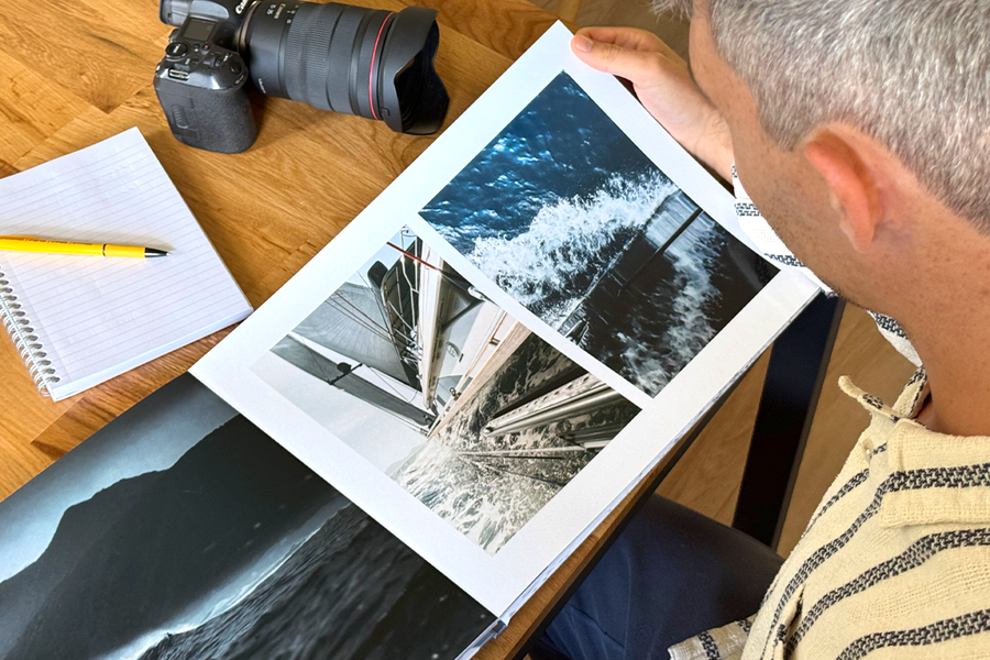 Fotograf Charl van Rooy schaut auf sein Portfolio, mit seiner Kamera und einem Notizbuch auf dem Tisch neben sich, und veranschaulicht posterXXLs Tipps zur Wahl der besten Vorlagen und Layouts für ein Fotografie-Portfolio.
