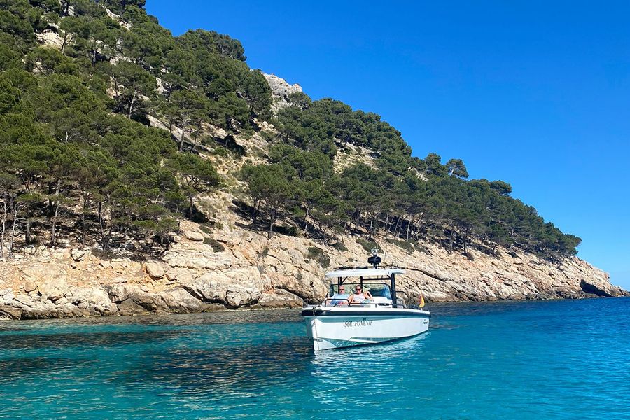 Ein Paar sitzt in einem Boot an einer wunderschönen, zerklüfteten Küste auf Ibiza, und fängt die ruhigere, entspannte Seite eines September-Urlaubs auf der Insel ein.