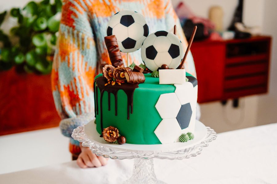 Eine Kindergeburtstagstorte, dekoriert mit Fußbällen und Schokoriegeln, und veranschaulicht posterXXLs Tipp, die Star-Torte zu fotografieren, bevor die Gäste eintreffen.