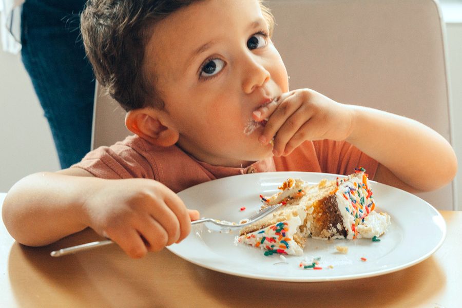 Ein kleiner Junge isst Geburtstagstorte, und veranschaulicht posterXXLs Foto-Checkliste zum Festhalten der besten Momente einer Kindergeburtstagsfeier.