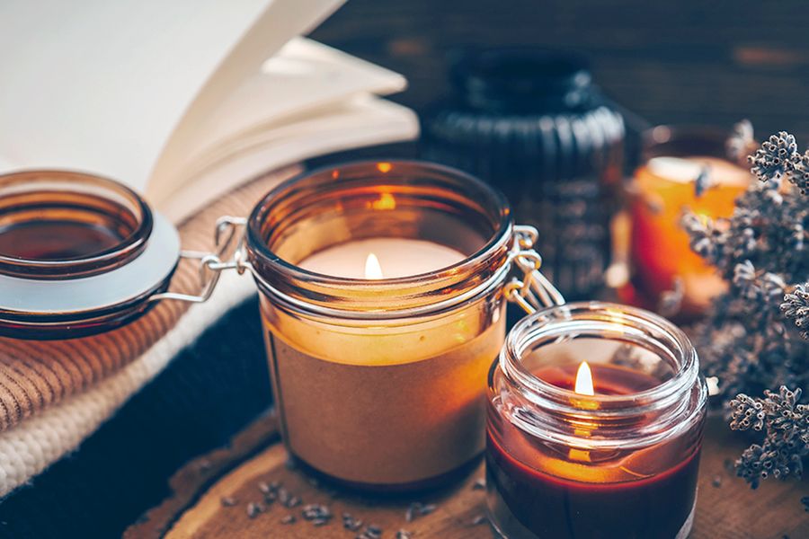 Ein paar brennende Kerzen stehen neben einem Blumenzweig, und veranschaulichen, wie Kerzen in posterXXLs Hygge-Deko-Tipps für eine gemütliche Herbstatmosphäre sorgen.