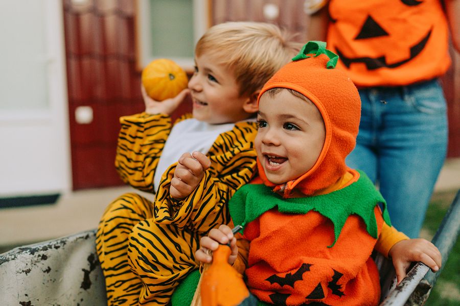 Zwei Kinder in Halloween-Kostümen, eines als Kürbis und eines als Tiger verkleidet, und veranschaulichen posterXXLs süße Halloween-Sprüche für Instagram.