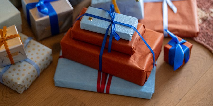 Ein Stapel Geschenke in orangefarbenem und hellblauem Papier, mit blauen Schleifen verziert, als Illustration für posterXXLs Tipps zu Black-Friday-Geschenkideen für Weihnachten.