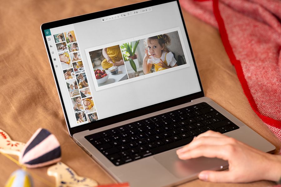 Hände an einem Laptop, auf dem der Online-Editor von posterXXL zu sehen ist, um zu zeigen, wie einfach es ist, ein Fotobuch als personalisiertes Weihnachtsgeschenk zu gestalten, passend zu posterXXLs Zeitplan, um ein personalisiertes Fotogeschenk zu erstellen.