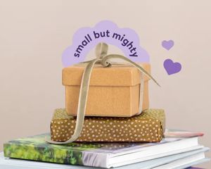 Ein Stapel posterxxl Fotobücher mit einem eingepackten Geschenk darauf – als Inspiration für personalisierte kleine Geschenke und liebevolle Fotogeschenk-Ideen.