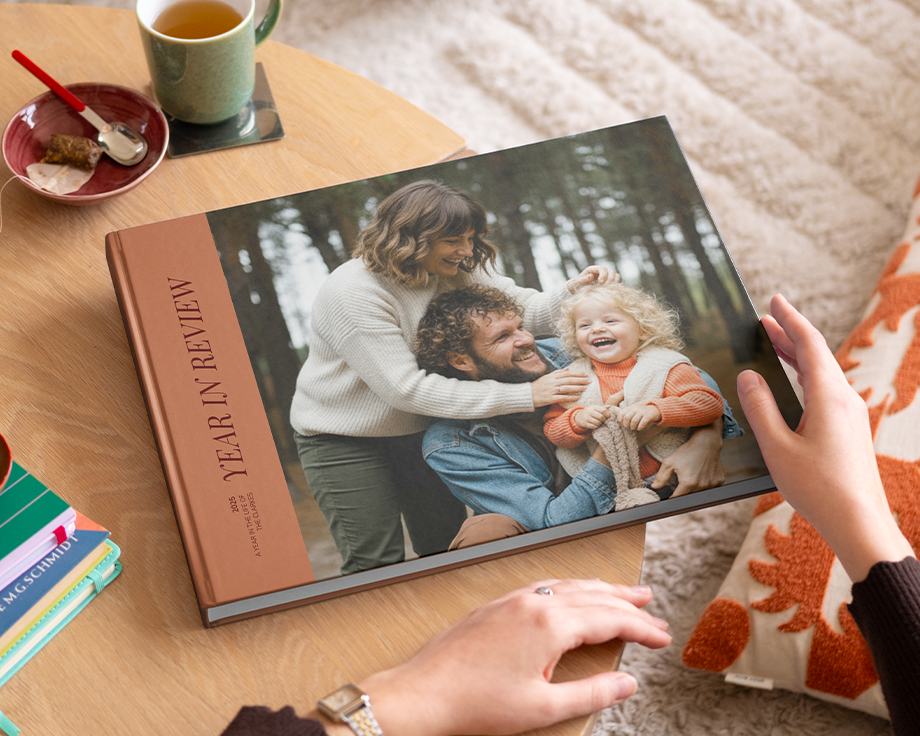 Ein posterXXL Coffee Table Fotobuch im Year-in-Review-Stil mit einem attraktiven Familienfoto auf dem Cover, das auf einem Couchtisch liegt – als Inspiration für ein personalisiertes Coffee Table Book.