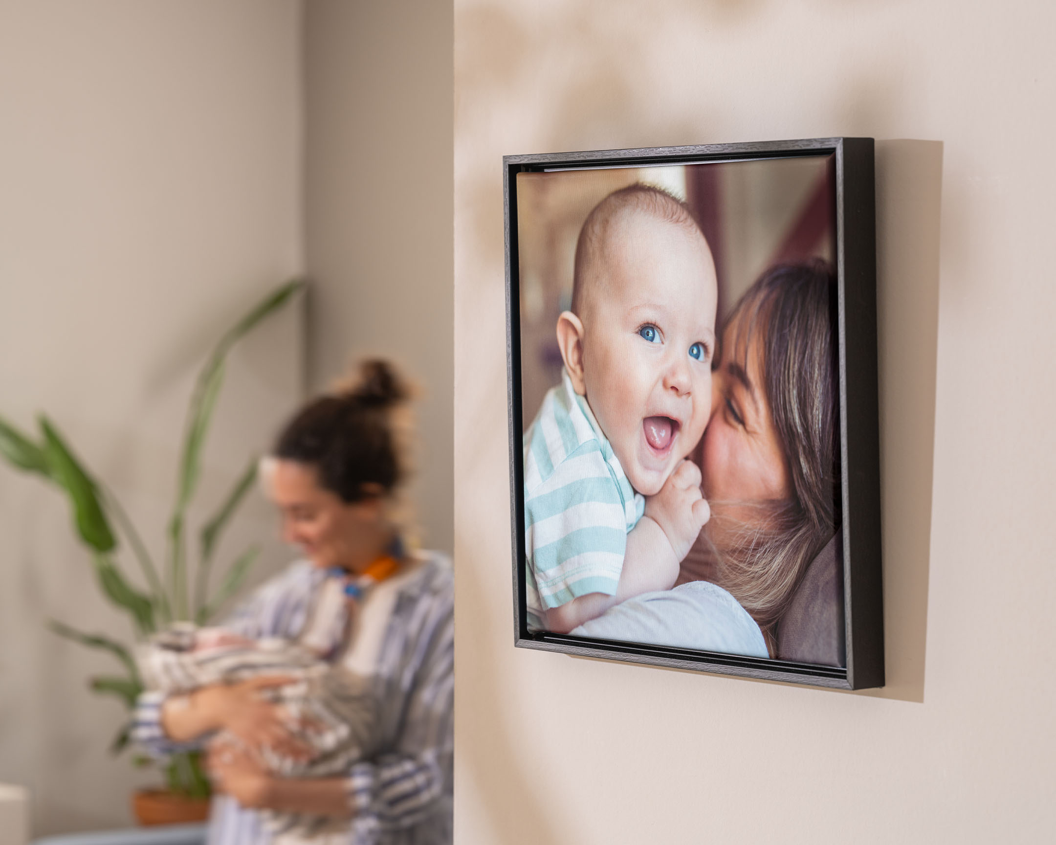 Gerahmtes Foto auf Leinwand an der Wand mit einer Mutter, die mit ihrem Baby kuschelt