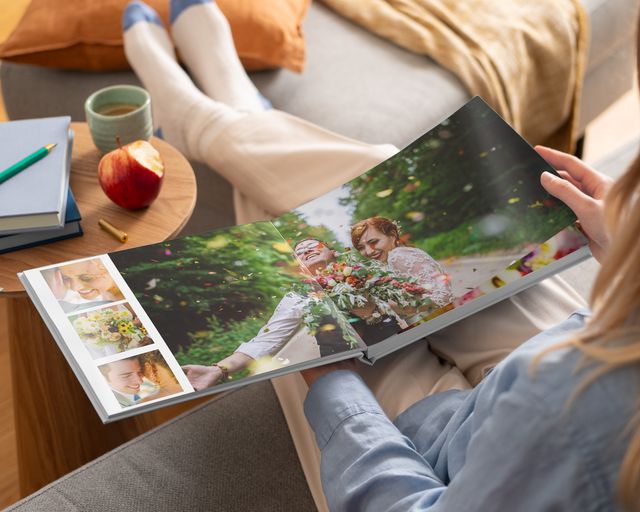 Eine Frau betrachtet ein offenes Layflat-Fotobuch mit Hochzeitsfotos.
