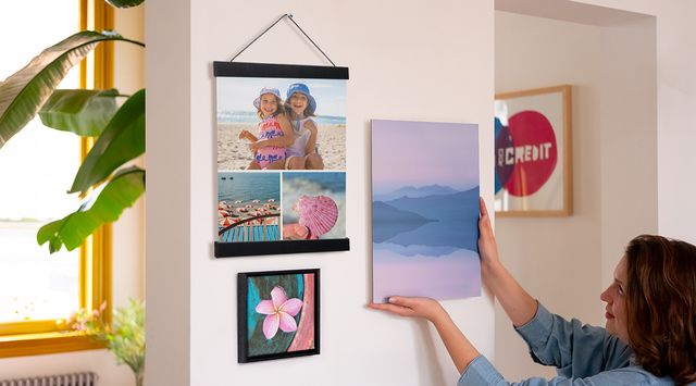 Person, die ein Bild neben zwei gerahmte Bilder hängt.
